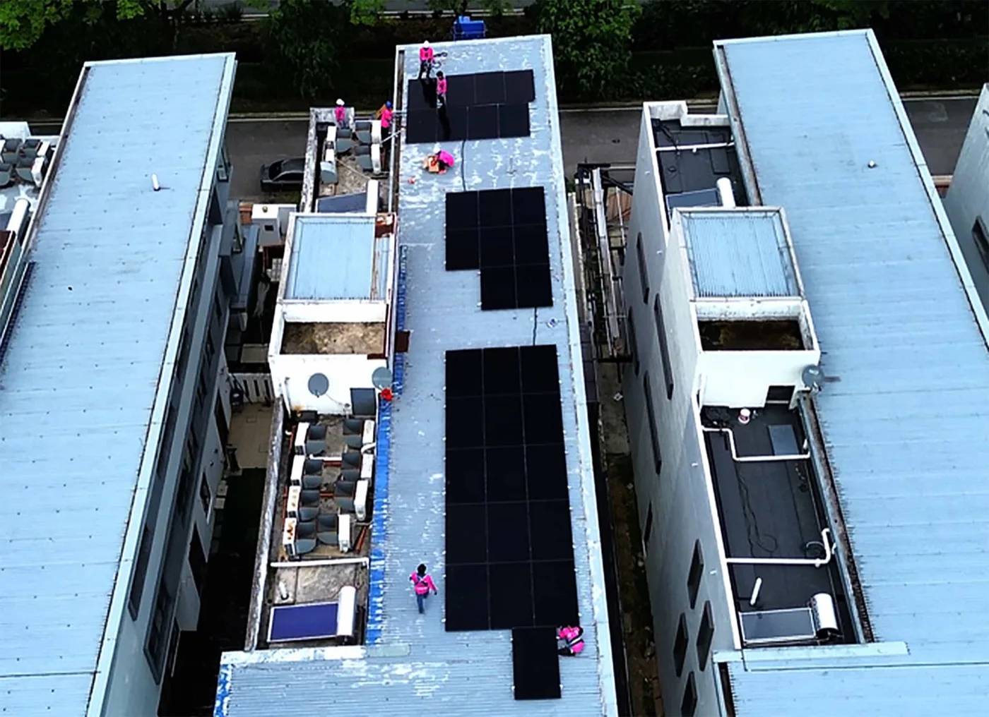 Aerial view of 32 panels on a long flat roof with the crew at work