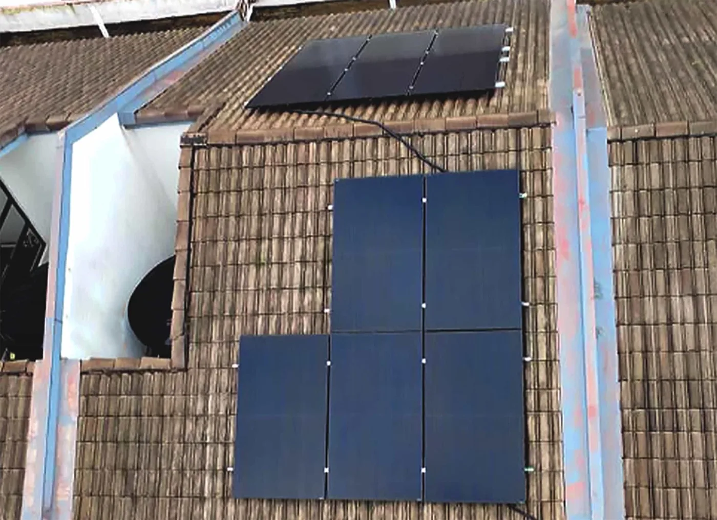 Eleven dark solar panels on a tiled terrace-house roof